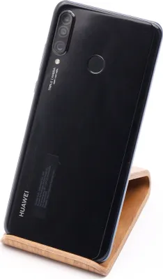 A black Huawei smartphone is displayed on a wooden stand against a white background.
