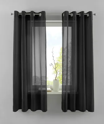 A window with black and sheer curtains, a white vase with a decorative branch, and a windowsill.
