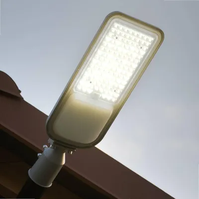 A street lamp is mounted on a brown structure against a light gray sky.