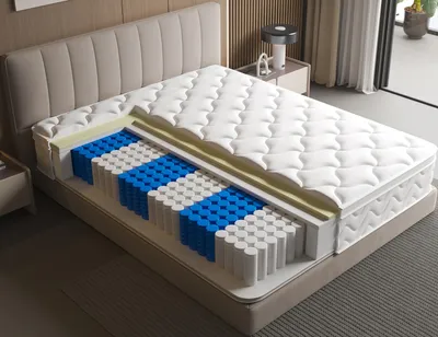 A cutaway view of a mattress showing its internal layers, including pocket springs and foam, placed on a bed frame.