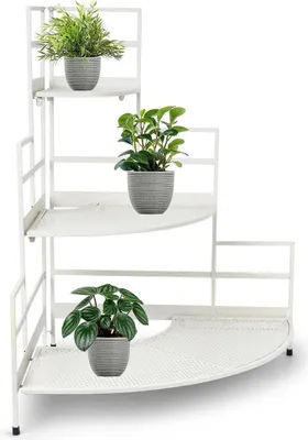 A white metal corner shelf with three tiers, holding three potted plants.