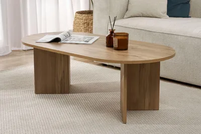 A wooden coffee table is placed on a rug in a living room setting, next to a sofa.