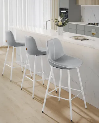 Three gray bar stools with white legs are lined up at a kitchen island.