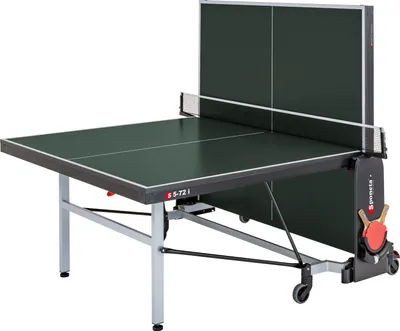A Sponeta S 5-72 i indoor table tennis table is shown from a slightly elevated, diagonal angle against a white background. The table is dark green with a white net stretched across the middle. The table has a foldable design with wheels for mobility. Two t