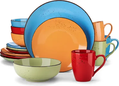 A collection of colorful ceramic dishes and mugs arranged in a studio setting.