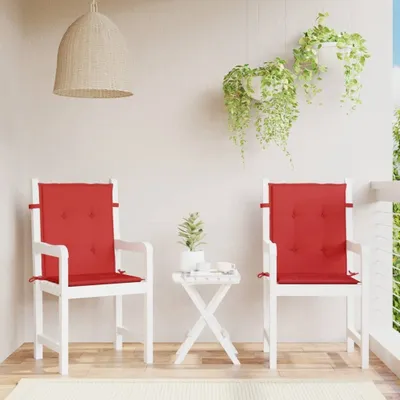 Two white chairs with red cushions are placed on a wooden deck, with hanging plants in the background.