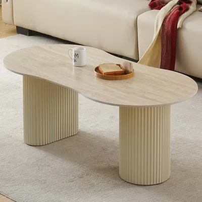 A modern coffee table with a travertine-look top and fluted cylindrical legs, placed on a rug in a living room setting.
