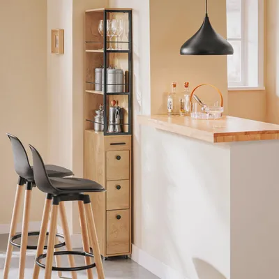 A kitchen or bar area with a tall storage unit, bar stools, and a countertop with bottles and an ice bucket.