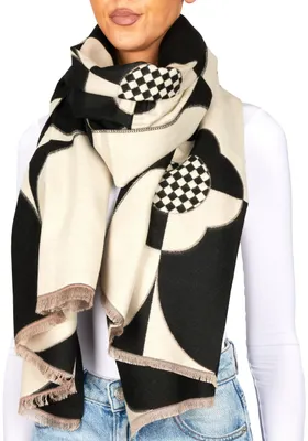 A woman wearing a white long-sleeved shirt and blue jeans, modeling a black and white patterned scarf.