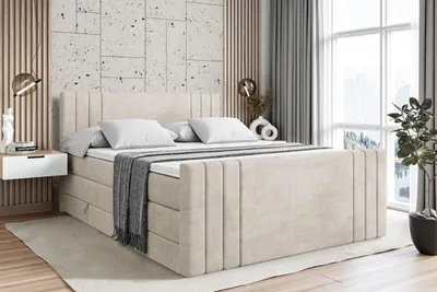 A bedroom scene featuring a large bed with pillows and a blanket, a bedside table, and a plant.