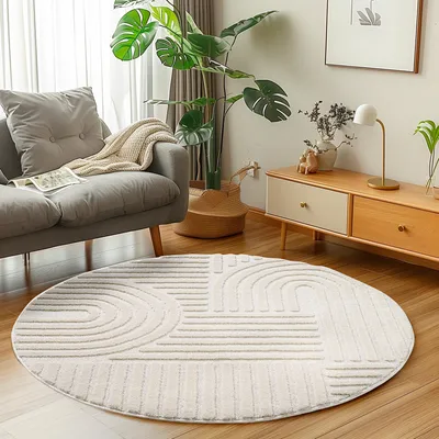 A round rug with a geometric pattern is placed on a wooden floor in a living room setting, next to a gray sofa and a wooden cabinet.