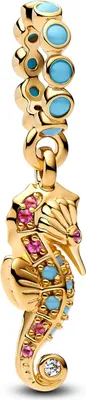 A close-up of a gold seahorse charm with blue and pink gemstones, hanging from a gold chain with blue gemstones.