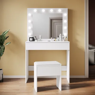 A white vanity table with a lighted mirror and a white stool in front of it, set against a yellow wall.