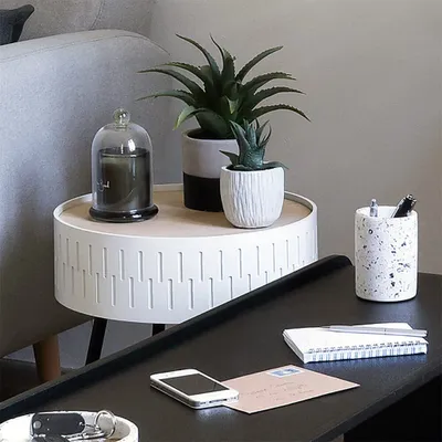 A side table with decorative items including plants, a candle, and office supplies on a desk.
