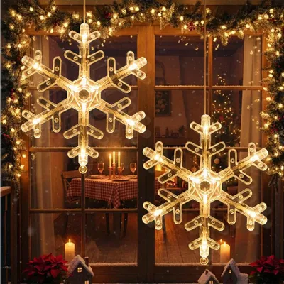 Christmas decorations hanging in a window, with a table set for dinner visible inside.