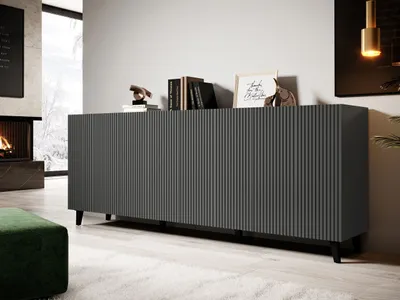 A modern gray sideboard with ribbed doors sits in a living room with a fireplace and a green ottoman.