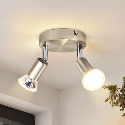 A close-up view of a modern, two-bulb ceiling light fixture made of brushed metal, mounted on a white ceiling.