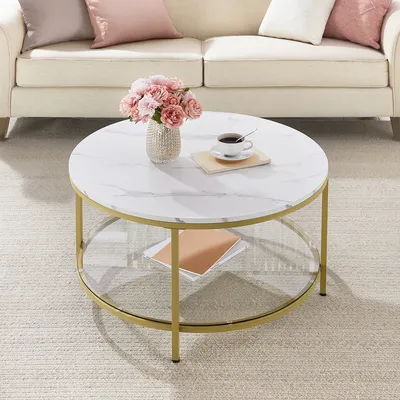 A coffee table with a marble top and gold legs is placed in a living room setting with a sofa and pillows.