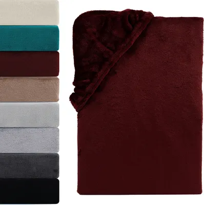 A stack of folded blankets in various colors next to a folded burgundy blanket.