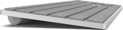 A close-up side view of a gray and silver wireless keyboard.