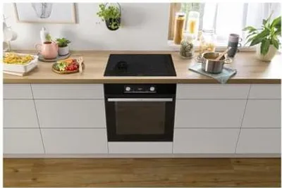 A kitchen counter with a built-in oven and stovetop, along with some kitchenware and plants.