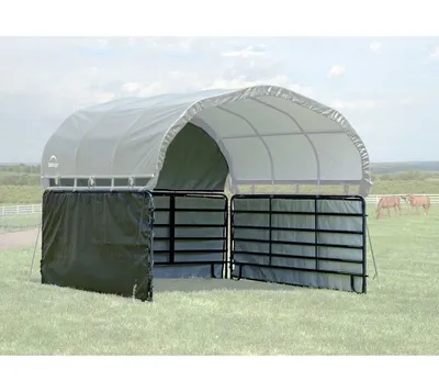 A shelter with side panels and gates in a grassy field with two horses in the background.