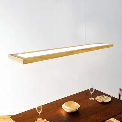 A wooden framed LED pendant light hangs above a dining table set with plates and glasses.