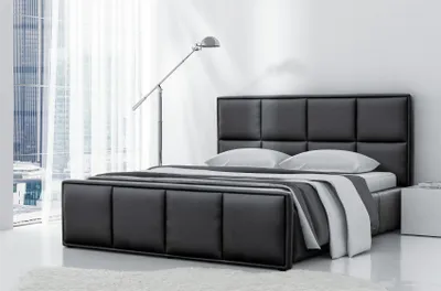 A modern bedroom with a black leather bed and a floor lamp.