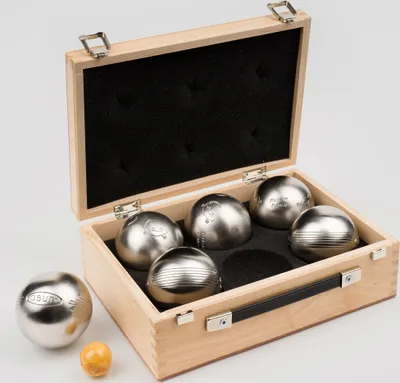 A wooden box containing six metal bocce balls and one small orange ball.