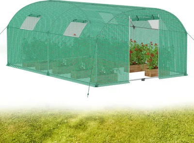 A green greenhouse with plants inside, set against a white background and a blurred green grassy foreground.