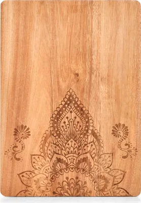 A close-up view of a wooden cutting and serving board with an intricate mandala-like design etched into the surface.