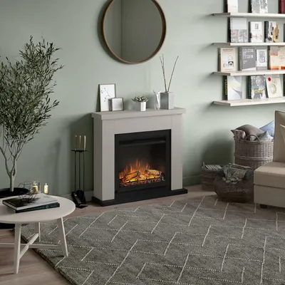 A cozy living room scene featuring an electric fireplace, a round mirror, bookshelves, and a coffee table.
