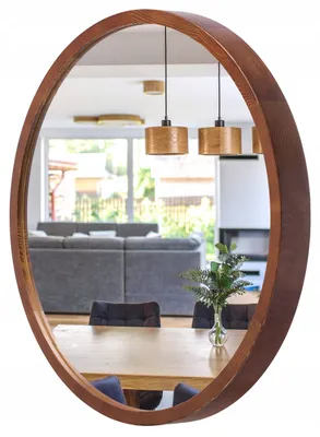 A mirror reflecting a dining and living area with furniture and pendant lights.