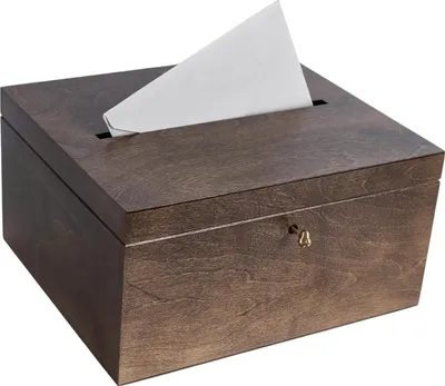 A wooden box with a slot on top and a keyhole on the front, with a piece of white paper sticking out of the slot.