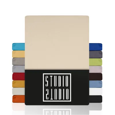 A stack of colorful fabric swatches or folded sheets are displayed next to a large, cream-colored sheet or fabric. A black band across the bottom features a white logo.