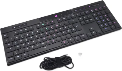 A black mechanical keyboard is shown on a white background with a coiled USB cable next to it.