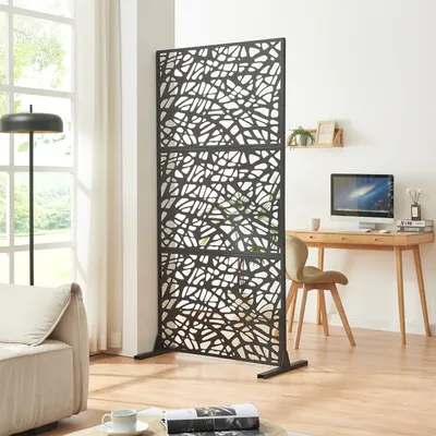 A room divider is placed in a living room setting, with a sofa and a desk with a computer visible.