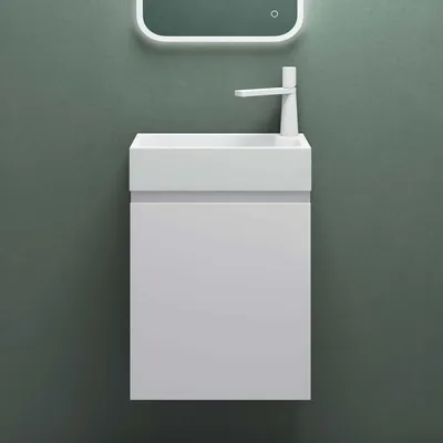A white sink and vanity unit mounted on a green wall.