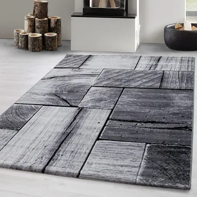 A close-up view of a rug with a wood plank pattern, placed on a light gray floor.