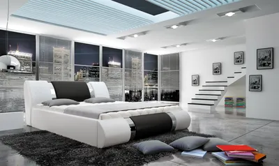 A modern bedroom with a large bed, city skyline view through windows, and a staircase with artwork.