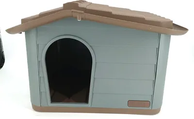 A plastic dog house with a brown roof and trim, and a gray body. It has an arched doorway.