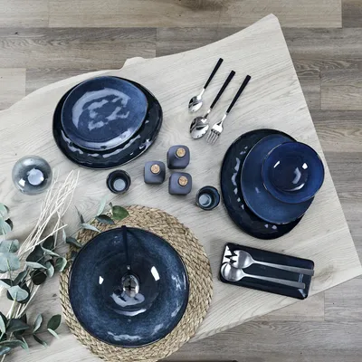 A collection of blue ceramic plates and bowls arranged on a wooden table with some decorative elements.