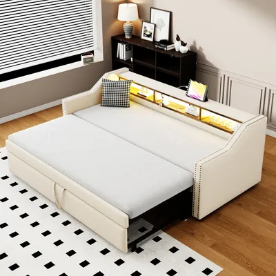 A beige sofa bed is shown in a room setting, with a rug on the floor and a window with blinds in the background.