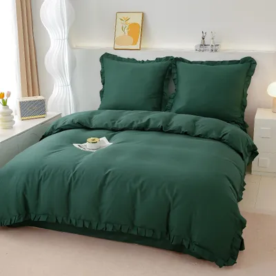 A neatly made bed with green bedding, including a duvet and two pillows with ruffled edges.