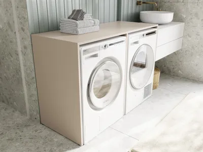 A modern bathroom with a washing machine and dryer cabinet.