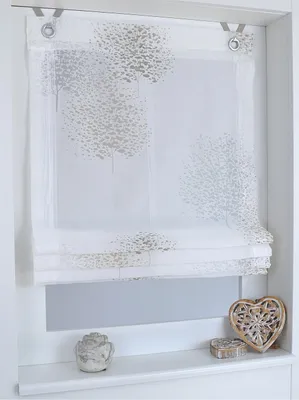 A white roman blind with a subtle tree pattern is shown hanging in a window recess.