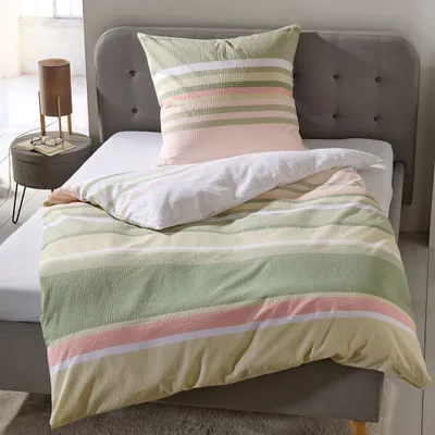 A neatly made bed with striped bedding and a pillow, in a bedroom setting.