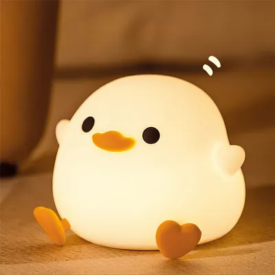A cute, glowing duck-shaped night light sits on a surface, emitting a warm white light.