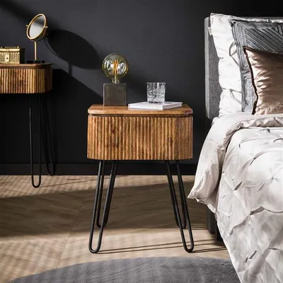 A bedside table with a lamp and a glass of water next to a bed.
