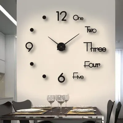 A large wall clock with numbers written out in words is mounted on a wall above a dining table set with plates and glasses.